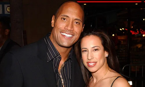 Dwayne "The Rock" Johnson and Dany Garcia smiling together while posing for a photo at a red carpet event. 