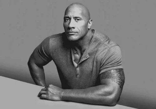 Black and white portrait of Dwayne "The Rock" Johnson in a henley shirt leaning forward.