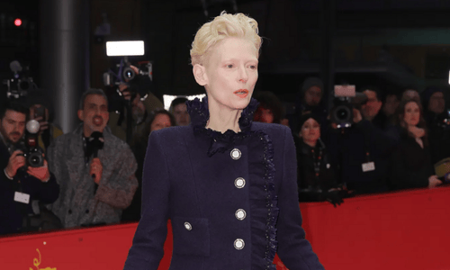 Tilda Swinton receiving the Lifetime Achievement Award at the Berlin Film Festival, posing in an elegant red-carpet look.