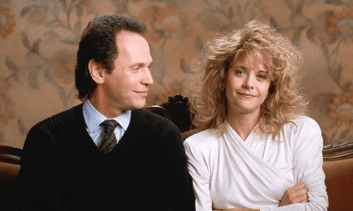 Billy Crystal, with a subtle smile, looks to his right at Meg Ryan, who is looking straight with a slight smirk.
