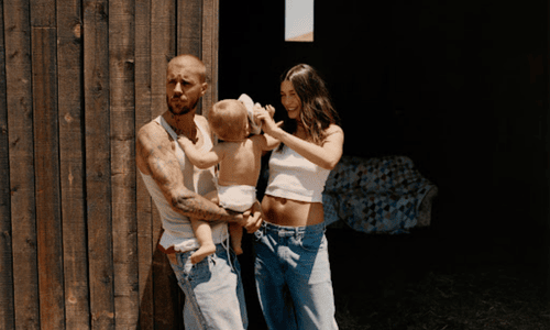 Justin Bieber with Hailey Bieber holding their baby in a casual outdoor family photo.