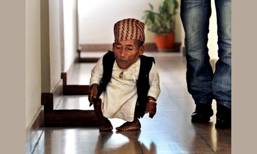 Chandra Bahadur Dangi, the shortest man ever recorded by Guinness World Records, walking indoors alongside another person.