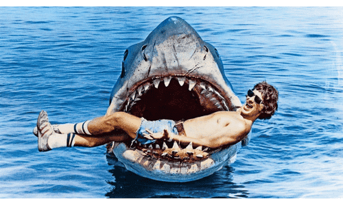 Iconic “Jaws” movie artwork featuring the shark rising toward a swimmer, from Steven Spielberg’s 1975 blockbuster. 