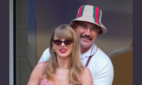 Taylor Swift and Travis Kelce attending a public event together, smiling and interacting during a high-profile appearance.