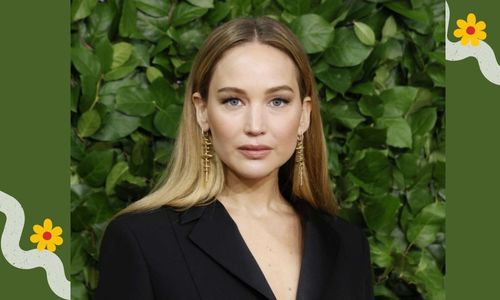 Jennifer Lawrence laughing after tripping on the red carpet at an awards event.