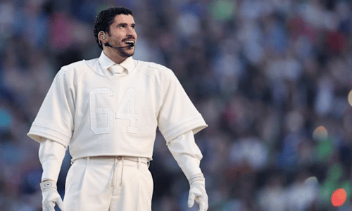 Bad Bunny performing on stage in a cream outfit with number 64, wearing a headset mic.