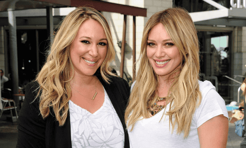 Haylie Duff and Hilary Duff smiling together at a public event.