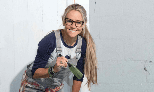 Nicole Curtis standing with a paint brush.