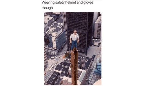 man standing on the tallest pole wearing a safety helmet and shoes, but still at risk.