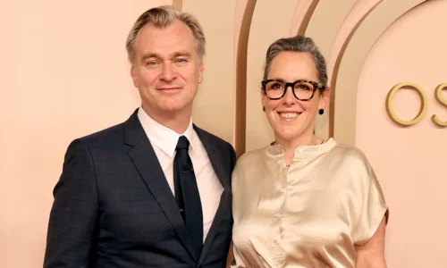 Producer Emma Thomas and director Christopher Nolan posing together on a red carpet.