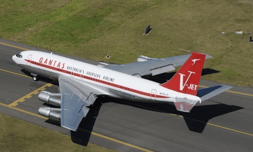 Actor John Travolta standing in front of his vintage Qantas-branded Boeing 707 at his home airport.