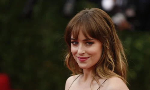 Dakota Johnson posing on a red carpet, reflecting on her journey since the "Fifty Shades" franchise.
