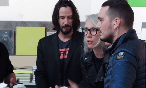 A close-up candid shot of Keanu Reeves and Alexandra Grant looking at each other during an interview.