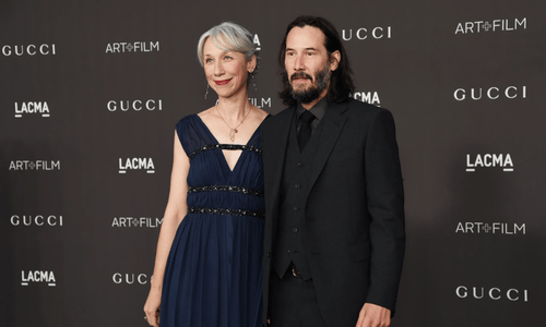 Keanu Reeves and artist Alexandra Grant laughing during a book launch event for their collaborative project.