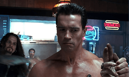 Arnold Schwarzenegger as the T-800 Terminator wearing sunglasses and holding a shotgun in a scene from Terminator 2.