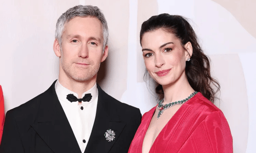 Anne Hathaway and husband Adam Shulman sharing a candid moment on a red carpet.
