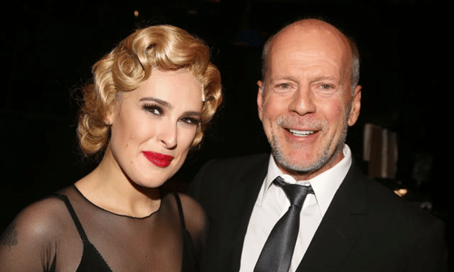 Bruce Willis smiling alongside his eldest daughter Rumer Willis at a red carpet event.