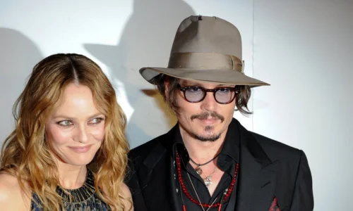 Johnny Depp wearing a fedora hat standing next to his former partner Vanessa Paradis on a red carpet.