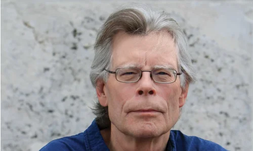 Close-up portrait of author Stephen King speaking at a microphone.