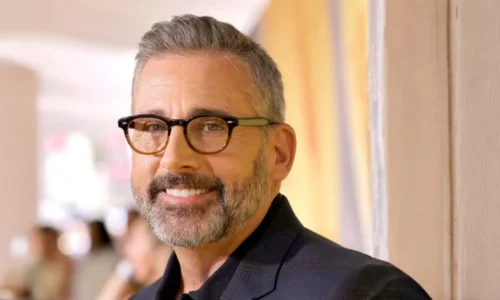 Close-up portrait of Steve Carell smiling and wearing thick black glasses.