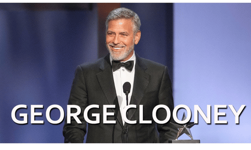 George Clooney smiling warmly while answering questions at a Hollywood press conference.