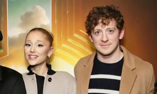 Singer Ariana Grande and actor Ethan Slater standing close together while posing at a red carpet event.