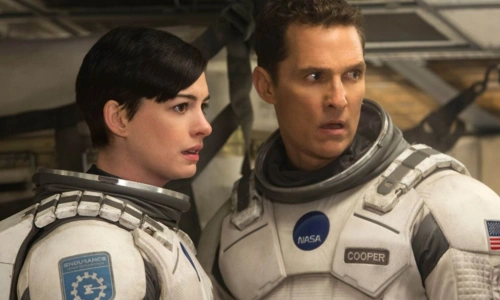 Anne Hathaway and Matthew McConaughey in spacesuits look surprised and distressed inside a spaceship in Interstellar.