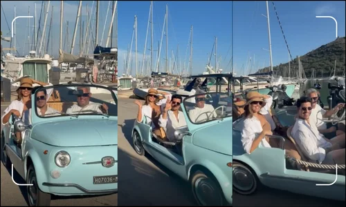 Jessica Alba and Danny Ramirez smiling in a vintage blue Fiat 500 in Tuscany, Italy.