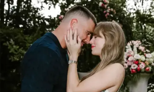 Taylor Swift and Travis Kelce embracing in a garden during their engagement announcement.