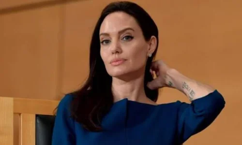 Angelina Jolie looking directly forward while wearing a professional blue dress.