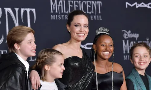 Angelina Jolie smiles on a red carpet at the Maleficent premiere with children Shiloh, Vivienne, Zahara, and Knox. 