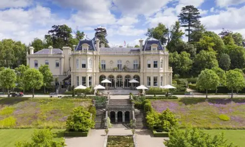 Exterior view of the luxurious Beaverbrook country house estate surrounded by lush gardens and green hills.