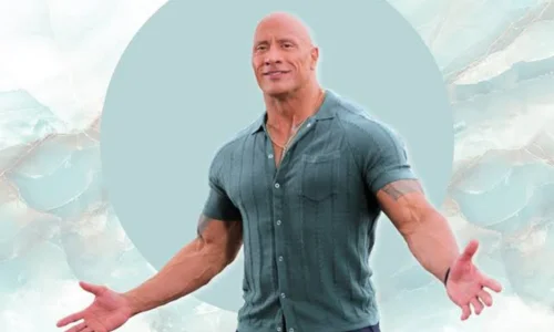 Dwayne Johnson smiling with arms open, wearing a green ribbed shirt and gold chain against a teal circle backdrop.