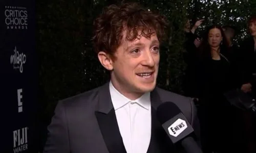 Ethan Slater posing in a gray suit at the Critics Choice Awards