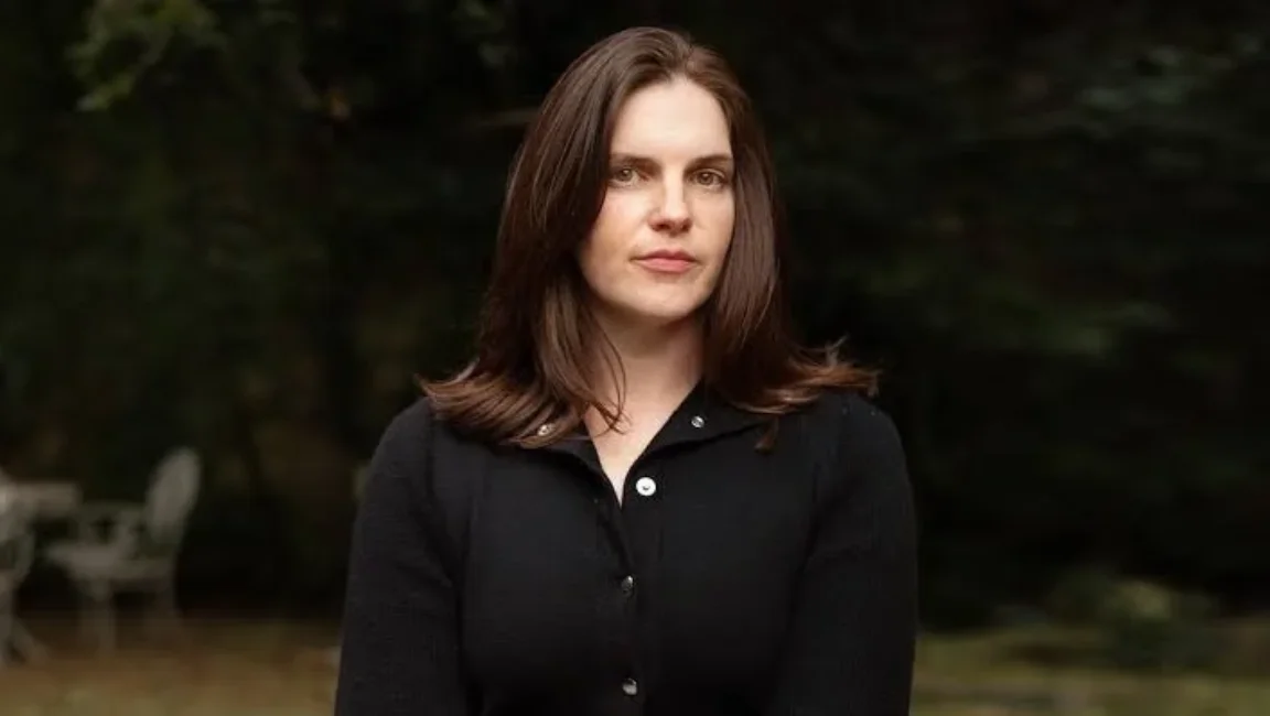 Film editor Jennifer Lame posing outdoors in a black button-down cardigan with blurred trees in the background.