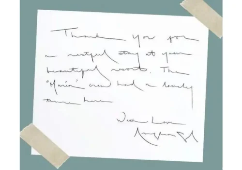 A piece of white paper taped down at the corners containing a handwritten thank-you note from Angelina Jolie.