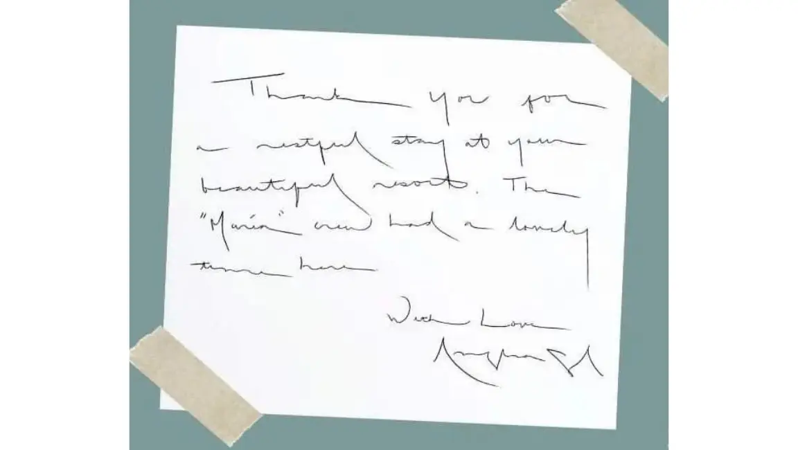 A piece of white paper taped down at the corners containing a handwritten thank-you note from Angelina Jolie.