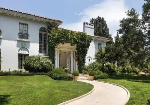 Historic white Los Angeles mansion overlooking a swimming pool and landscaped lawn
