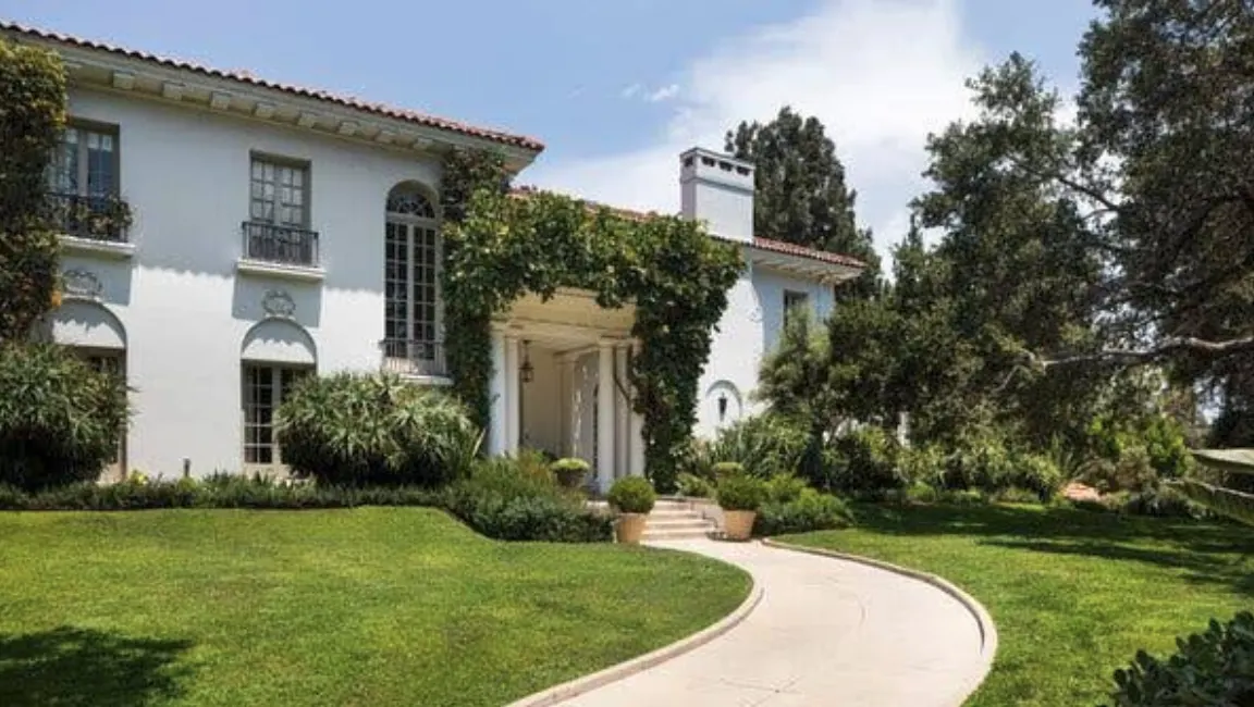 Historic white Los Angeles mansion overlooking a swimming pool and landscaped lawn