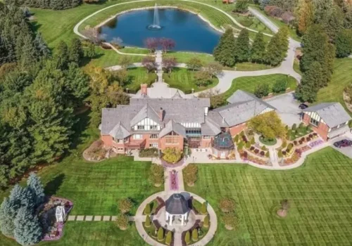 Aerial view of a large mansion surrounded by trees and open land