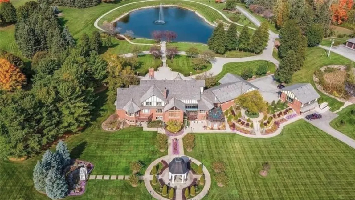 Aerial view of a large mansion surrounded by trees and open land