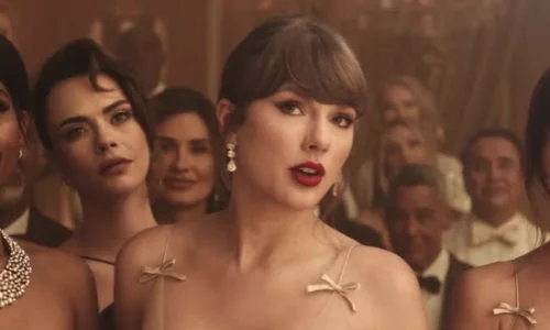 Female singer wearing a cream dress and red lipstick in a glamorous music video scene